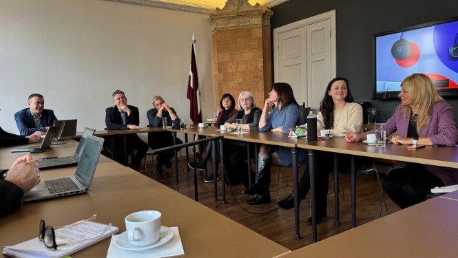 Attēlā attēloti diskusijas dalībnieki, kuri seiž pie galda