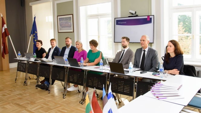 Attēlā attēlots delegācija, kas seiž sanāksmes zālē.