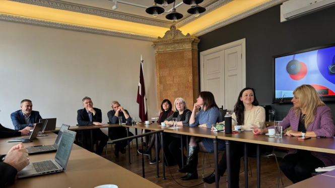 Attēlā attēloti diskusijas dalībnieki, kuri seiž pie galda