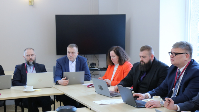 Attēlā attēloti darba grupas dalībnieki, kuri seiž pie galda