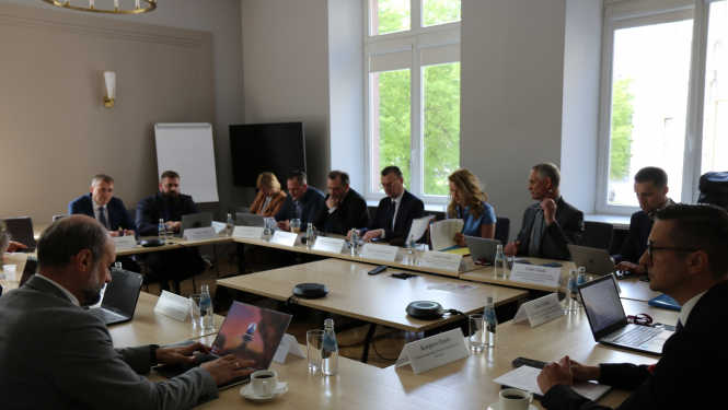 Attēlā attēlota darba grupa, kas sēdes laikā sēž pie galda