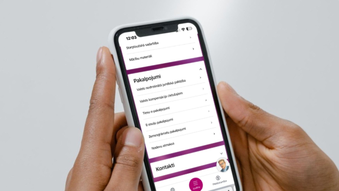 attēlā cilvēks tur rokās telefonu