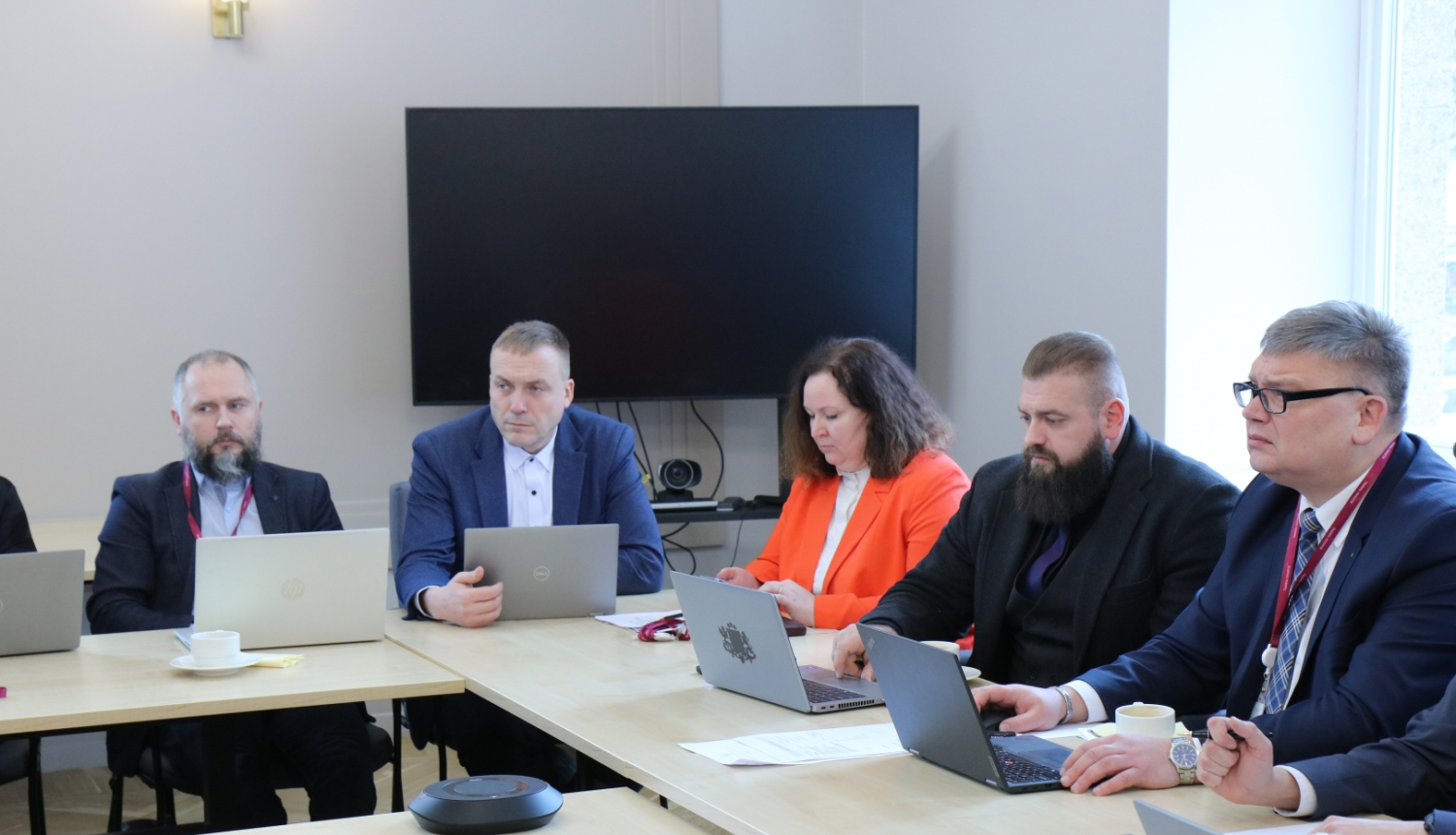 Attēlā attēloti darba grupas dalībnieki, kuri seiž pie galda